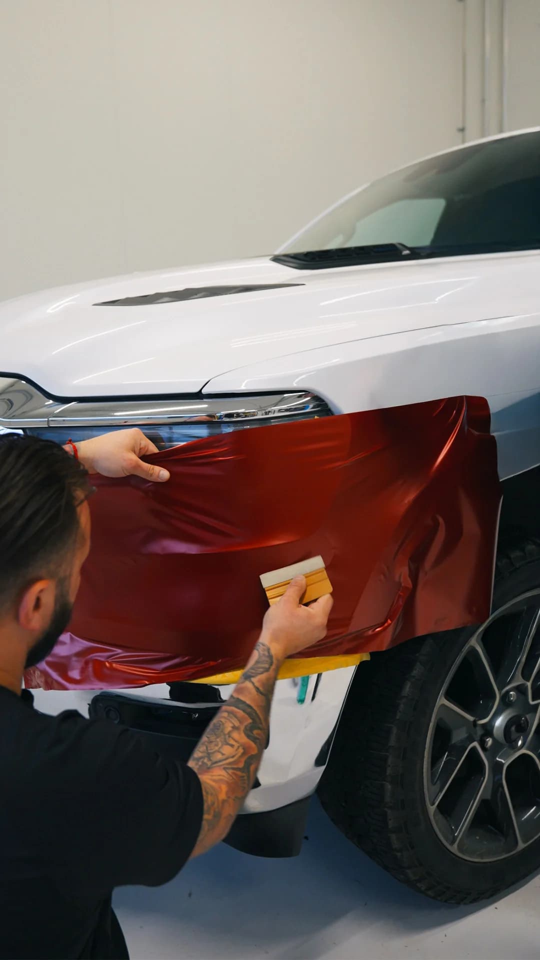 Autofolierung: rote Folie wird auf eine Motorhaube aufgezogen